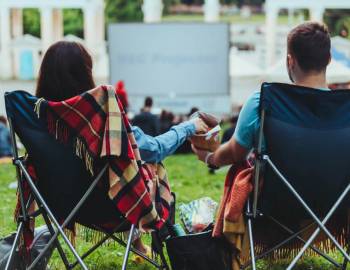 A couple in lawn chairs watching a movie outdoors at Movie Night at Shelter Cove Community Park