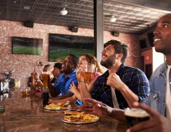 People at Street Meet enjoying food and drink while watching a sporting event