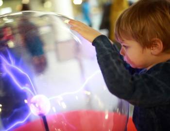 A child touching an energy ball at The Sandbox Museum on Hilton Head Island